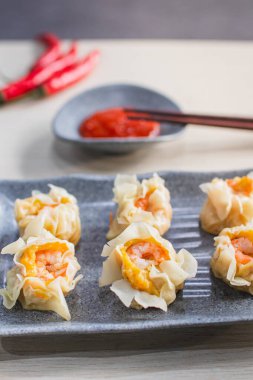 Buharda pişmiş karides, acı biber, domates ve sosla servis edilen ahşap masa.