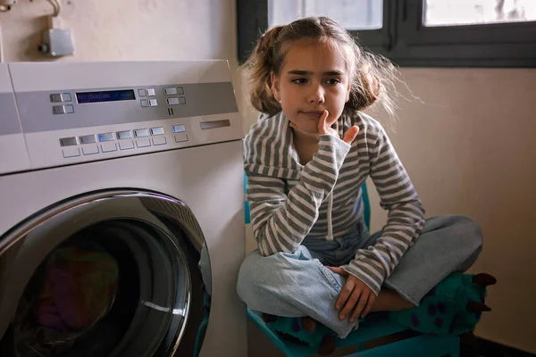Eco-conscious teenage girl waits in common laundry. Sustainability and responsible living. Efforts to save resources, conserve water, energy, and money. Eco-lifestyle in action