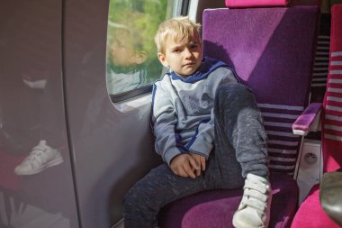 Tren yolculuğundaki dalgın çocuk, güneş ışığı dalgın ruh halini vurguluyor. Düşüncelere dalmış, aletlerden uzak bir an.