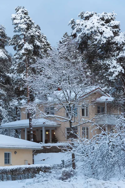 snow-covered yellow house and trees in a winter forest
