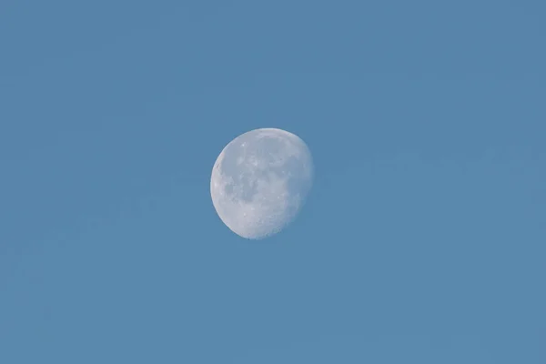 incomplete moon in a blue sky