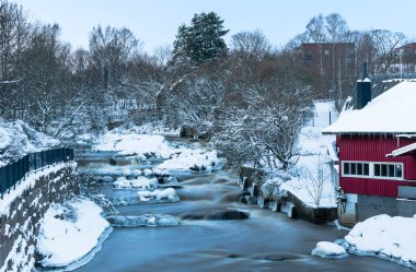 Ön planda kırmızı bina ve arka planda Helsinki Finland nehri olan karlı bir manzara