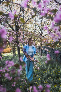 Çiçek açan kiraz çiçekleri parkında mavi gömlekli güzel bir kadın.