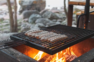 Doğada ızgarada et sosisi pişirmek. 