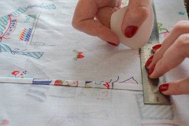 Terzi kadın, terzi stüdyosunda elbise dikmek için tebeşirle desen çiziyor.