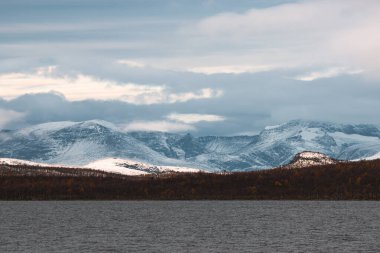 Bulutlu bir günde göl ve dağların güzel manzarası, Finlandiya, Laponya