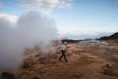 female tourist walks on orange gravel at Myvatn Geothermal area, Iceland clipart