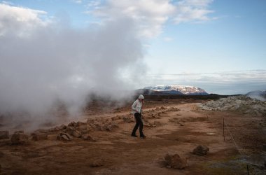 Kadın turist İzlanda 'nın Myvatn Jeotermal bölgesinde turuncu çakıl üzerinde yürüyor