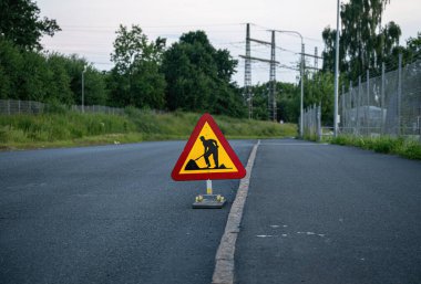 Kırsaldaki yolda trafik levhası var. Uyarı yol işareti