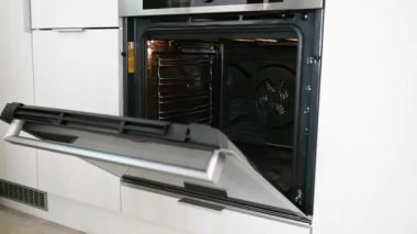 Kadın elleri fırına metal bir ızgara koyar.