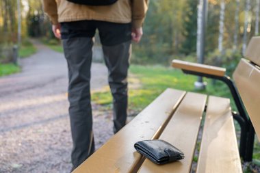 Adam cüzdanını kaybettiği banktan ayrılıyor. Parktaki bankta unutulmuş cüzdan.