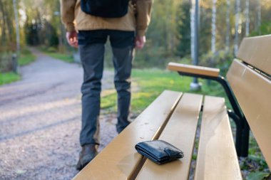 Adam cüzdanını kaybettiği banktan ayrılıyor. Parktaki bankta unutulmuş cüzdan.