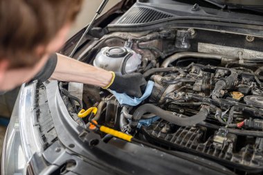 Eldivenli tamirci, iyi aydınlatılmış bir garajda araç ve giysi ile bir araba motoruna bakım, otomotiv ve onarım kavramı