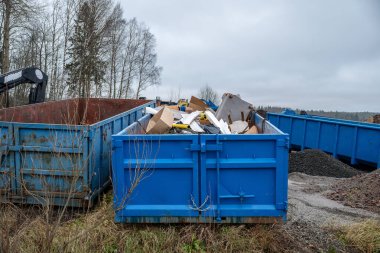 Çeşitli atık maddelerle dolu büyük mavi sanayi konteynerleri
