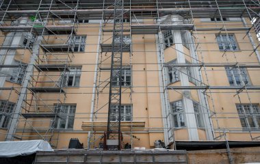 Scaffolding surrounding a beige building under renovation, featuring large windows and an industrial urban setting. Concept of construction clipart