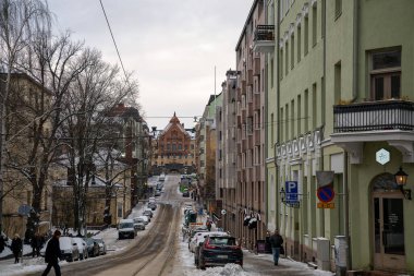 Helsinki, Finlandiya - 23 Kasım 2024: Arabaları, yayaları ve renkli binaları olan karlı bir cadde