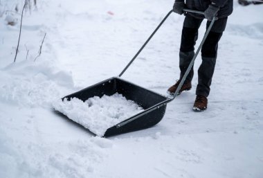 Karlı bir yolda büyük bir kar küreğiyle kar temizleyen biri. Açık hava işleri konsepti