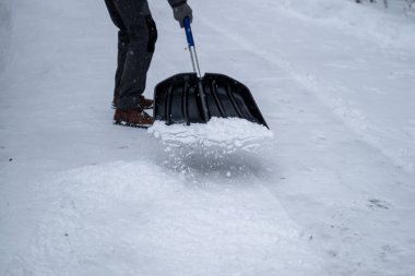 Kar küreği kullanarak karlı arka planda kar temizleyen biri. Kış görevi kavramı