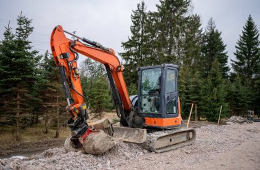 İnşaat alanında hidrolik kolu ve kovası olan turuncu kazıcı