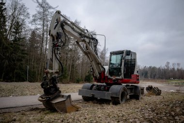 Hidrolik kollu ve kovalı büyük tekerlekli kazıcı ormanın yakınındaki çamurlu zeminde.. 