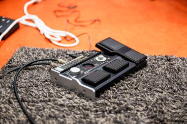 Bir müzik stüdyosunun gitar efekt işlemcisinin düğmeleri ve dipnotu ile yakın plan görüntüsü.