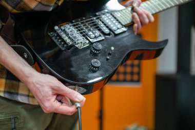 Müzik stüdyosuna elektro gitar kablosu takan kişi