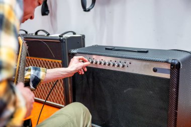 Gitarist kayıt stüdyosundaki elektro gitarın amplifikatörünü ayarlıyor