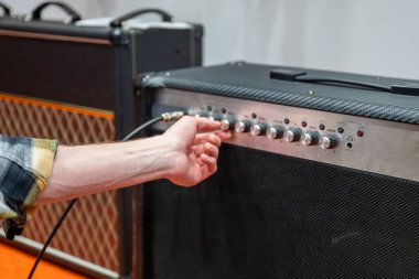 Gitarist, müzik stüdyosundaki elektro gitarın amplifikatörünü ayarlıyor.