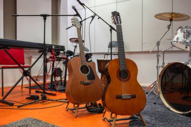 Stüdyoda bateri, klavye ve mikrofonları olan iki akustik gitar.