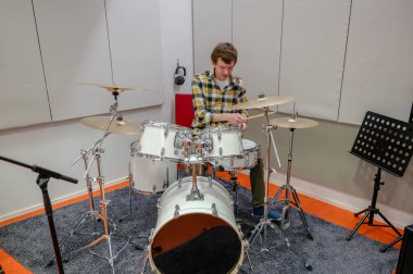 Man playing drum kit in a soundproof studio clipart