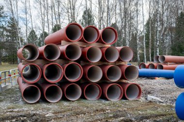 İnşaat alanındaki ahşap paletlerin üzerine istiflenmiş kırmızı inşaat boruları.. 