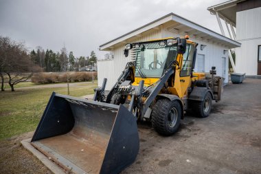 Sarı ön yükleyici ormanlık alana yakın yol kenarına park edilmiş.. 