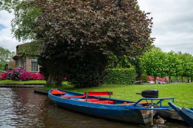 Hollanda 'daki ünlü Giethoorn köyünün manzarası. Kanalları ve teknesi var.