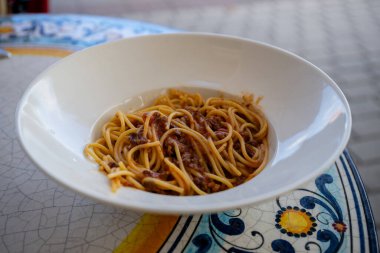 Seramik mozaik masa üzerinde beyaz kasede servis edilen et soslu spagetti bolonezi.. 