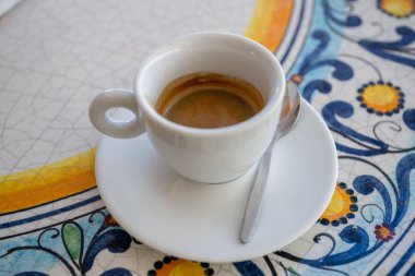 Açık havada renkli seramik masada beyaz bardakta taze demlenmiş espresso.. 