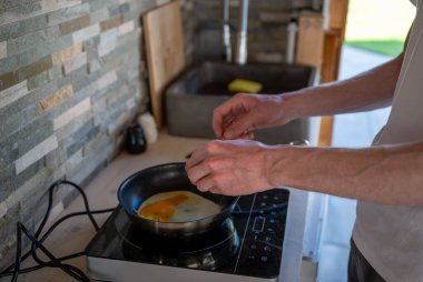 İnsan kızartma tavasında çırpılmış yumurta pişiriyor. Ev yemeği kavramı.. 