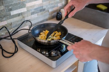 İnsan kızartma tavasında çırpılmış yumurta pişiriyor. Ev yemeği kavramı.. 