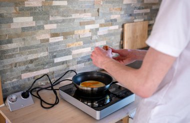 İnsan kızartma tavasında çırpılmış yumurta pişiriyor. Ev yemeği kavramı.. 