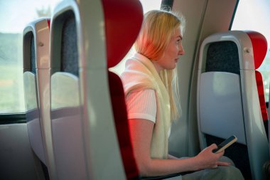 Modern trende kırmızı koltuklu bir kadın akıllı telefon kullanıyor.. 