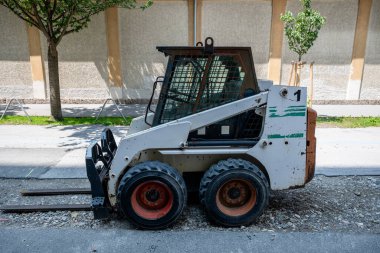 Şehirdeki yol inşaatında küçük fren dümeni yükleyicisi. 