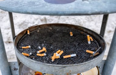 Metalden yapılmış kirli kül tablasında sigara izmaritleri kullanılmış.. 