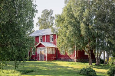 Finlandiya kırsalında yaz yeşili ile çevrili geleneksel kırmızı ahşap ev. 