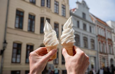 Güneşli bir günde tarihi şehir binalarına dayanan iki vanilyalı dondurma külahı.. 