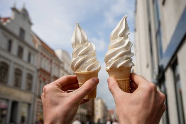 Güneşli bir günde tarihi şehir binalarına dayanan iki vanilyalı dondurma külahı.. 