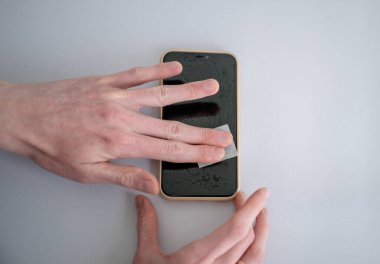 Ekran koruyucu uygulamadan önce akıllı telefon ekranını kuru mendille temizleyen adam. 
