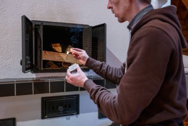 Sıcak kışlık ev ısıtması için şöminede odun yakan adam.. 