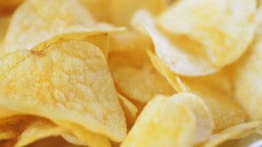Masanın üzerinde bir dağ dolusu patates cipsi yatıyor. Altın çipler yakın plan. Bir sürü abur cubur, makro video. Yüksek kalite 4k görüntü