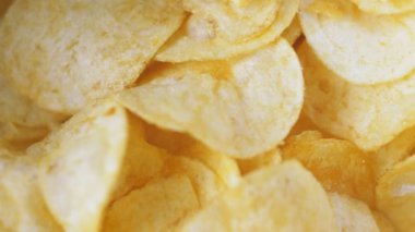 Masanın üzerinde bir dağ dolusu patates cipsi yatıyor. Altın çipler yakın plan. Bir sürü abur cubur, makro video. Yüksek kalite 4k görüntü