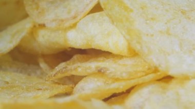 Masanın üzerinde bir dağ dolusu patates cipsi yatıyor. Altın çipler yakın plan. Bir sürü abur cubur, makro video. Yüksek kalite 4k görüntü