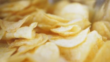 Masanın üzerinde bir dağ dolusu patates cipsi yatıyor. Altın çipler yakın plan. Bir sürü abur cubur, makro video. Yüksek kalite 4k görüntü